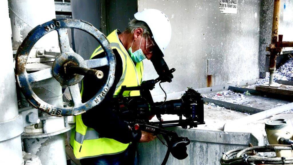 Camera Operator shooting in hard hat and mask