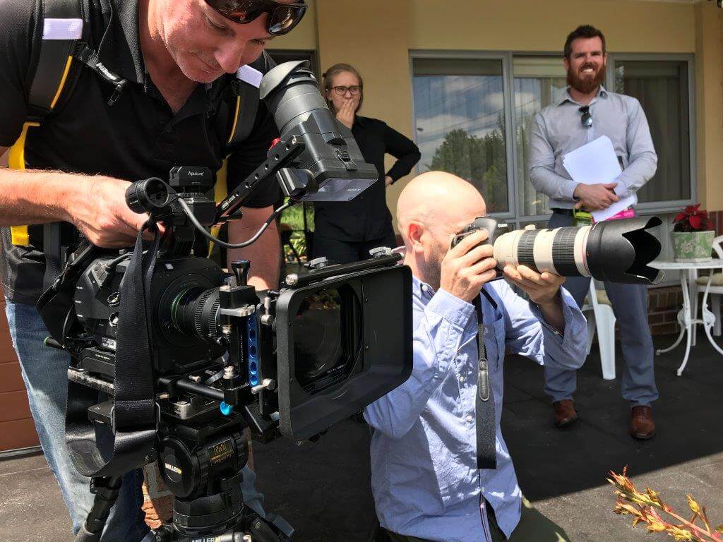 Camera Operator and Photographer in action while client looks on