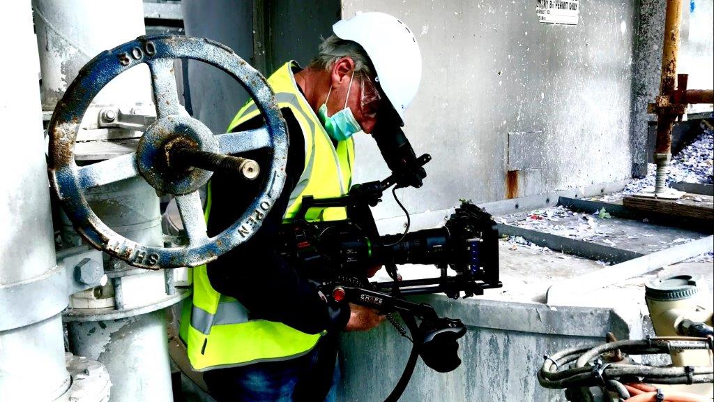 Camera Operator in hard hat and mask on an industrial worksite
